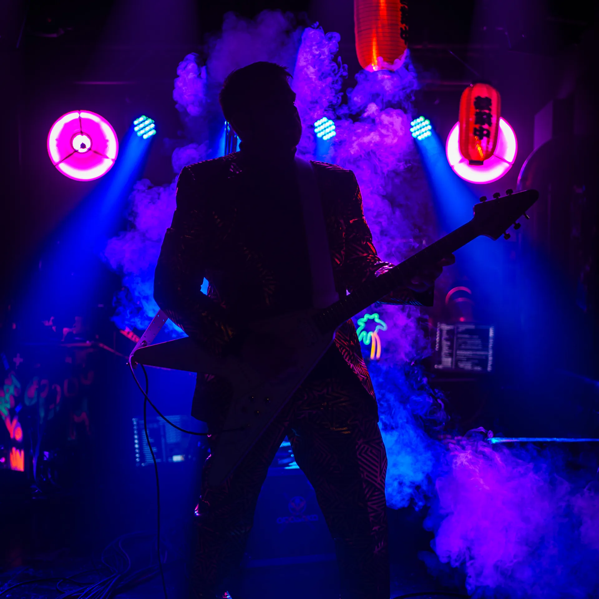 Gitarista King of Synthos v dyme a svetlách reflektorov
